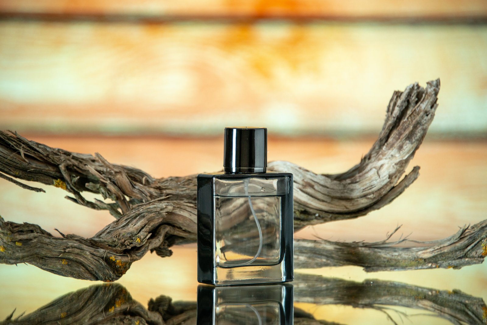 front-view-rectangular-cologne-bottle-branch-rotten-wood-yellow-background-copy-place